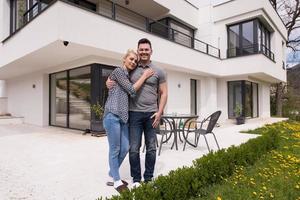 pareja abrazándose frente a una nueva casa de lujo foto