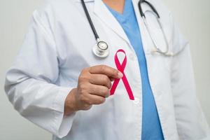 Breast cancer, Asian doctor woman with pink ribbon, symbol of World Breast Cancer Day. photo