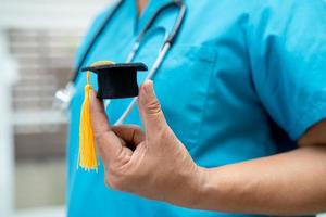 el estudio de un médico asiático aprende con un sombrero de brecha de graduación en la sala del hospital, un concepto de medicina inteligente y brillante. foto