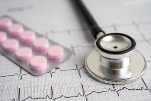 Stethoscope on electrocardiogram with capsule pill, heart wave, heart attack, cardiogram report. photo