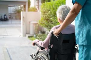 Caregiver help and care Asian senior or elderly old lady woman patient sitting in wheelchair on ramp at nursing hospital, healthy strong medical concept photo