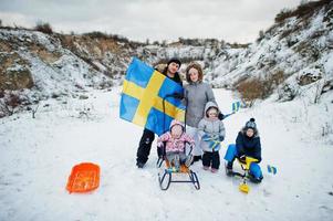 familia escandinava con bandera de suecia en el paisaje sueco de invierno. foto