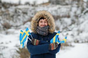 Scandinavian man with Sweden flag in winter swedish landscape. photo