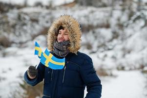 Scandinavian man with Sweden flag in winter swedish landscape. photo