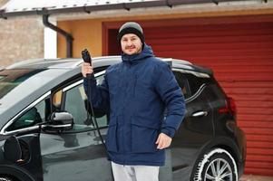 joven cargando su coche eléctrico en invierno. concepto de transporte ecológico. foto