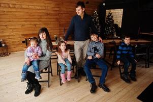 Family in modern wooden house sitting against table with christmas tree, spending time together in warm and love. photo