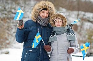 Scandinavian couple with Sweden flag in winter swedish landscape. photo