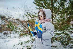 niña escandinava con bandera de suecia en el paisaje sueco de invierno. foto