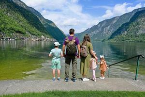 espalda de una familia con tres hijos sobre el lago de los alpes austriacos en hallstatt, salzkammergut, austria. foto