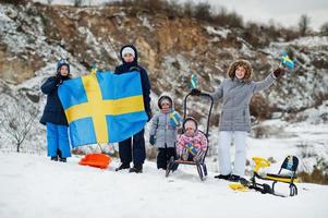 familia escandinava con bandera de suecia en el paisaje sueco de invierno. foto