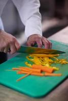 chef in hotel kitchen  slice  vegetables with knife photo