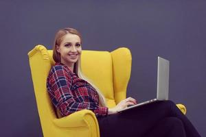 startup business, woman  working on laptop and sitting on yellow armchair photo