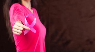 October Breast Cancer Awareness month, adult Woman in pink shirt hand holding Pink Ribbon for supporting people living and illness. International Women, Mother and World cancer day concept copy space photo