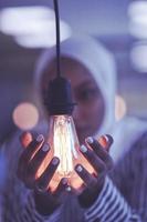 internet of things concept woman holding hands around bulb photo