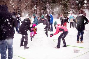 group of young people making a snowman photo