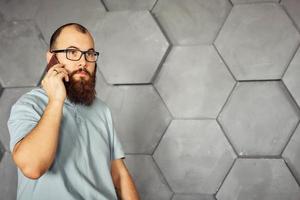 hombre barbudo con gafas hablando por un teléfono móvil foto