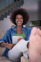 mujer afroamericana en casa con tableta digital foto