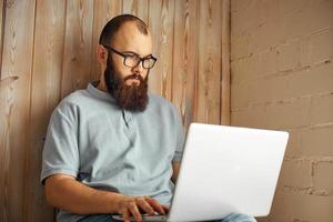 lifestyle successful freelancer man with beard achieves new goal with laptop in loft interior. photo