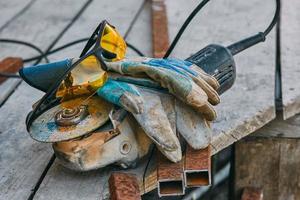 Angle grinder, safety goggles, gloves, a piece of pipe. Worker tools photo