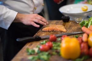Chef hands preparing marinated Salmon fish photo