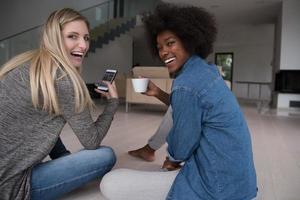 young multiethnic women sit on the floor and drinking coffee photo