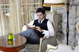 young man reading book and relaxing in luxury indoor photo