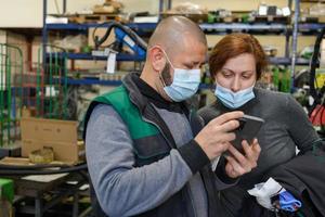 Industrial workers with face masks protected against corona virus discussing about production in factory. People working during COVID-19 pandemic. photo