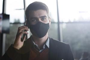 business man wearing coronavirus  medical face mask while using smartphone photo