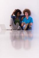 multiethnic couple sitting on the floor with a laptop and tablet photo