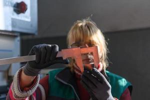 una mujer que trabaja en una fábrica moderna para la producción y procesamiento de metales, preparando y midiendo materiales que van al procesamiento de máquinas cnc foto