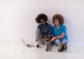 pareja multiétnica sentada en el suelo con una laptop y una tableta foto