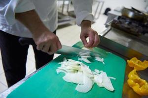 chef in hotel kitchen  slice  vegetables with knife photo