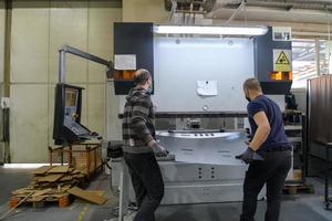 Turkey, 2022 - two workers wearing a protective mask due to a coronavirus pandemic, working in a modern factory and preparing a program and materials for a cnc machine photo