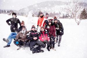 group portait of young people posing with snowman photo