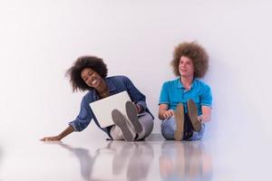 multiethnic couple sitting on the floor with a laptop and tablet photo