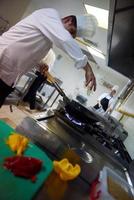 chef en la cocina del hotel prepara comida con fuego foto