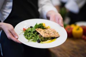 Chef hands holding dish of fried Salmon fish fillet photo