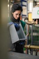 a woman working in a modern metal factory assembles parts for a new machine photo