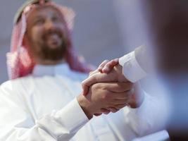 Business meeting with arab man and shaking each other hands in greetings and introduction discussing and planning within modern office in background photo