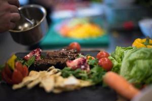 Chef hand finishing steak meat plate photo