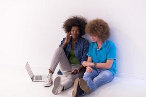 multiethnic couple sitting on the floor with a laptop and tablet photo