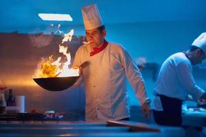 chef in hotel kitchen prepare food with fire photo