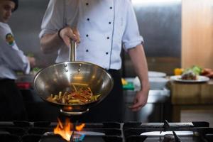 chef flipping vegetables in wok photo