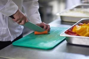 chef in hotel kitchen  slice  vegetables with knife photo