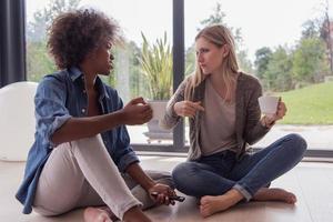 multiethnic women sit on the floor and drinking coffee photo