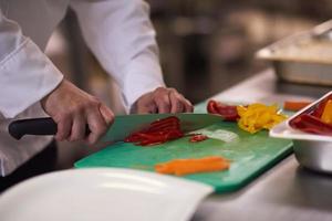 chef in hotel kitchen  slice  vegetables with knife photo