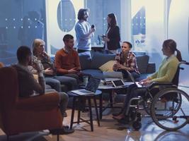 mujer de negocios discapacitada en silla de ruedas al reunirse con su diverso equipo de negocios haciendo una lluvia de ideas en la oficina foto