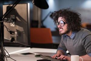 man working on computer in dark startup office photo