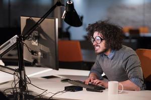 hombre trabajando en una computadora en una oficina de inicio oscura foto