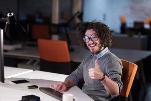 hombre trabajando en una computadora en una oficina de inicio oscura foto